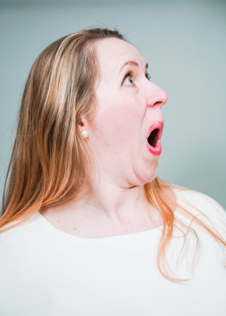 Funny studio portrait of middle aged woman with surprised face.