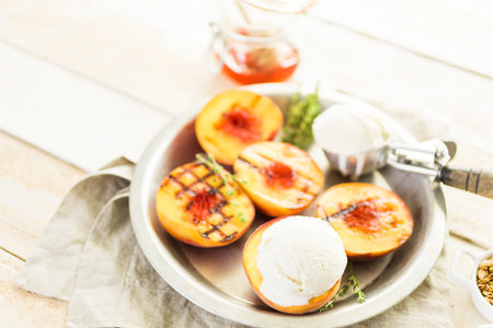 Organic grilled peaches with scoop of vanilla ice cream.の写真素材
