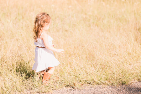 Little girl in a white sun dress playing outside.の写真素材