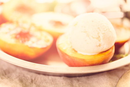 Organic grilled peaches with scoop of vanilla ice cream.