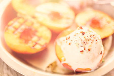 Organic grilled peaches with vanilla ice cream, honey, and pecans.の写真素材