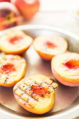 Organic grilled peaches with fresh thyme on a metal plate.の写真素材