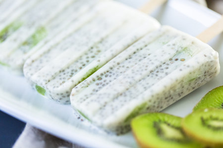Kiwi coconut chia popsicles on a white serving plate.の写真素材