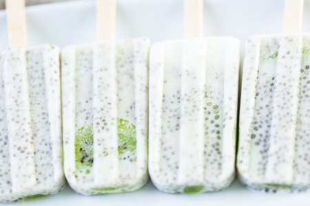 Kiwi coconut chia popsicles on a white serving plate.の写真素材