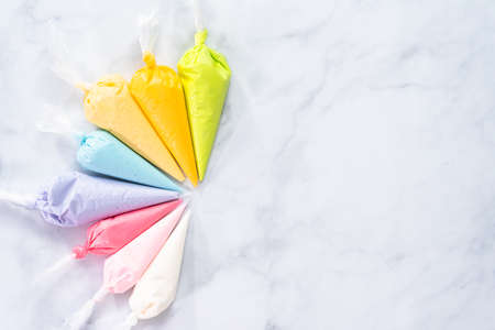 Flat lay. Piping bags with pastel color royal icing to decorate Easter sugar cookies.の写真素材