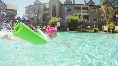 POV point of view - Little girl having fun with swim noodle in outdoor swimming pool.のeditorial素材
