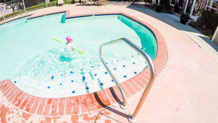 POV point of view - Little girl having fun with swim noodle in outdoor swimming pool.のeditorial素材