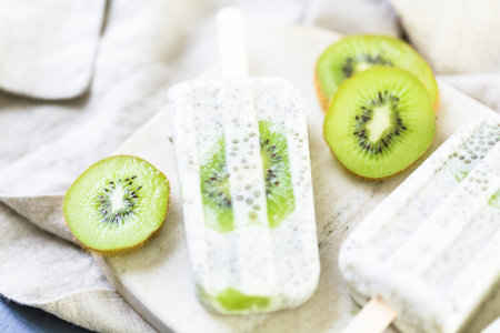 Kiwi coconut chia popsicles on granite board.の写真素材