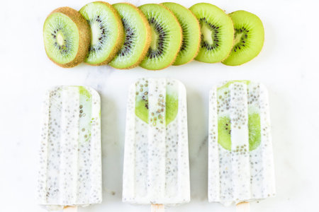 Kiwi coconut chia popsicles on white marble board.の写真素材