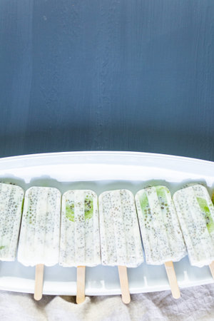 Kiwi coconut chia popsicles on a white serving plate.の写真素材