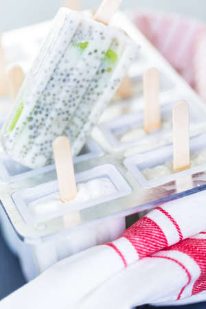 Homemade kiwi coconut chia popsicles in frozen ice pop maker.の写真素材