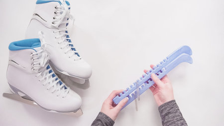 Flat lay. Putting on blue blade guards on white figure skates.