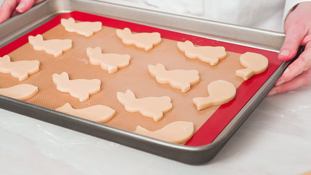 Step by step. Unbaked Easter sugar cookies arranged for baking on a baking sheet.