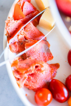 A white tiered platter filled with smoked salmon, cheese, crackers, and fresh fruits and berries.