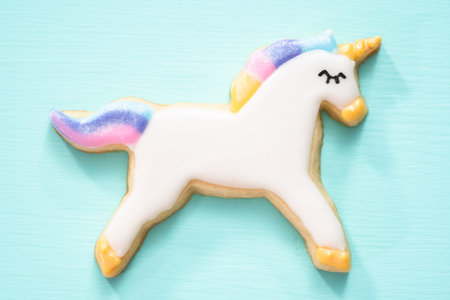 Unicorn sugar cookies decorated with royal icing and food glitter on a blue background.