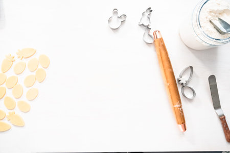 Flat lay. Cutting out shapes with metal cookie cutter out of the sugar cookie dough.