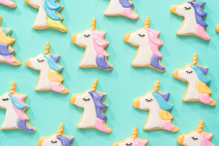 Flat lay. Unicorn sugar cookies decorated with royal icing and food glitter on a blue background.