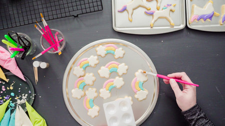Flat lay. Step by step. Painting food glitter on top of unicorn sugar cookies with royal icing.