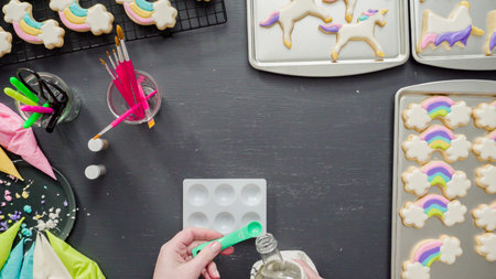 Flat lay. Step by step. Painting food glitter on top of unicorn sugar cookies with royal icing.