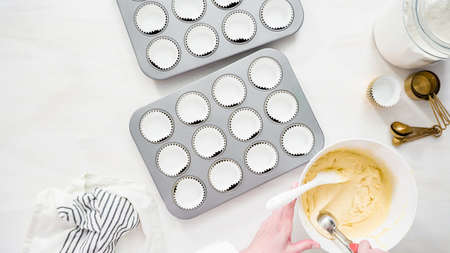 Flat lay. Step by step. Scooping cupcake batter into cupcake liners to bake vanilla cupcakes.の写真素材