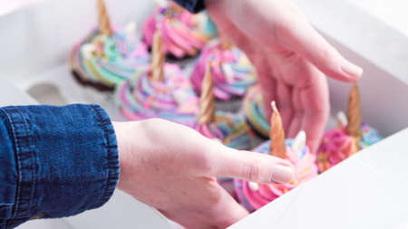 Step by step. Boxing unicorn chocolate cupcakes into a white cupcake box.の写真素材