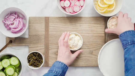 Flat lay. Step by step. Assembling bagel brunch board with smoked salmon and fresh vegetables.の写真素材