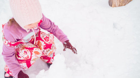 Little girl playing in snow near her house in typical suburbia.の写真素材