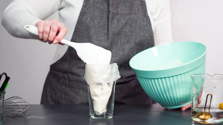 Step by step. Pouring royal icing into the piping bag to decorate sugar cookies.