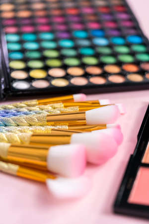 New eyeshadow palette with makeup brushes on a pink background.の写真素材