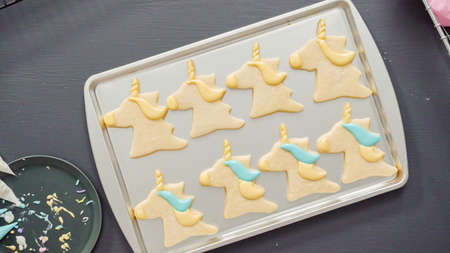 Flat lay. Decorating unicorn sugar cookies with multi-color royal icing.の写真素材