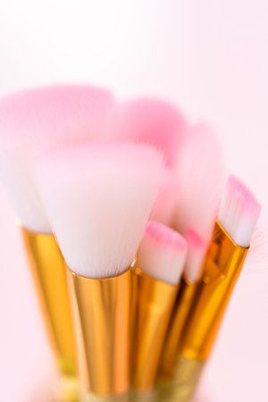 Unicorn color makeup brushes on a pink background.