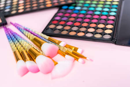 New eyeshadow palette with makeup brushes on a pink background.の写真素材