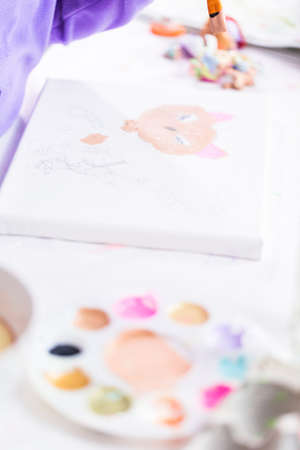 Little girl painting on canvas with arcylic paint.の写真素材