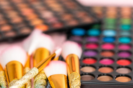 New eyeshadow palette with makeup brushes on a pink background.
