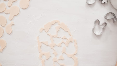 Step by step. Flat lay. Cutting sugar cookie dough with Easter shaped cookie cutters.