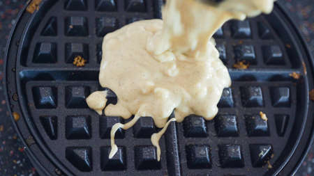 Making homemade waffles in an electric waffle maker.の写真素材