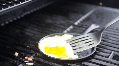 Cooking eggs in cast iron skillet on a gas grill.の写真素材