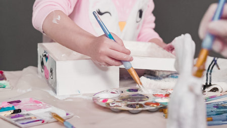Painting with a white acrylic paint unicorn paper mache figurine.