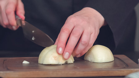Step by step. Dicing yellow onion on a wood cutting board.