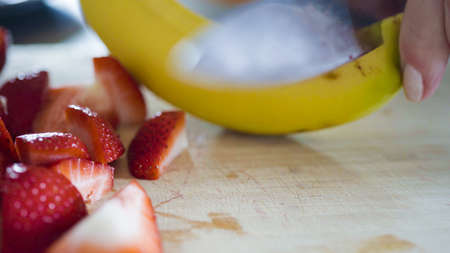 Slicing fresh banana on a wood cutting board.の写真素材