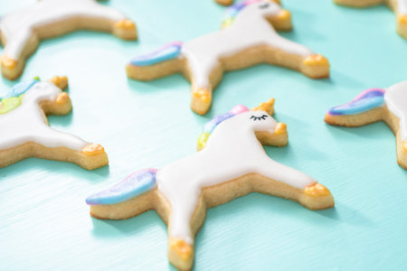 Unicorn sugar cookies decorated with royal icing and food glitter on a blue background.の写真素材