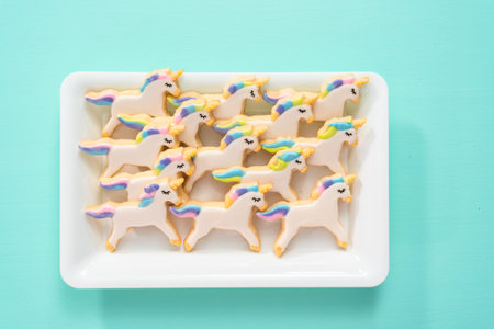 Flat lay. Unicorn sugar cookies decorated with royal icing and food glitter on a blue background.の写真素材