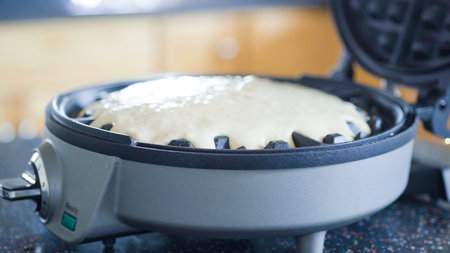 Making homemade waffles in an electric waffle maker.