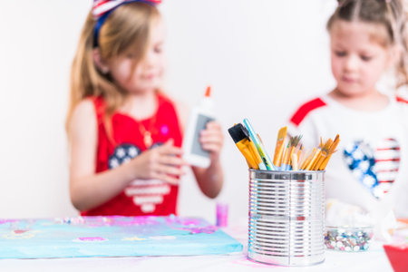 Little girls are painting on canvas on July 4th party.