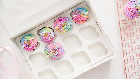Flat lay. Step by step. Boxing unicorn chocolate cupcakes into a white cupcake box.
