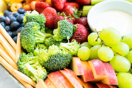 Snack board with fresh fruit, vegetables, crackers, and dips.