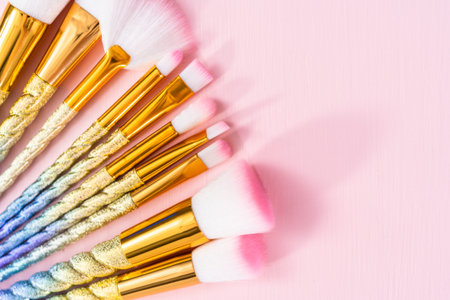 Unicorn color makeup brushes on a pink background.