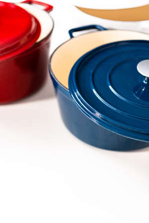 Red, white and blue enameled cast iron covered round dutch ovens on a whjite background.の写真素材
