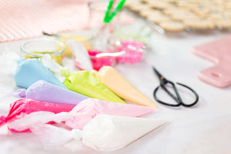 Piping bags with pastel color royal icing to decorate Easter sugar cookies.の写真素材
