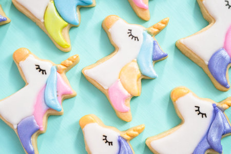 Unicorn sugar cookies decorated with royal icing and food glitter on a blue background.